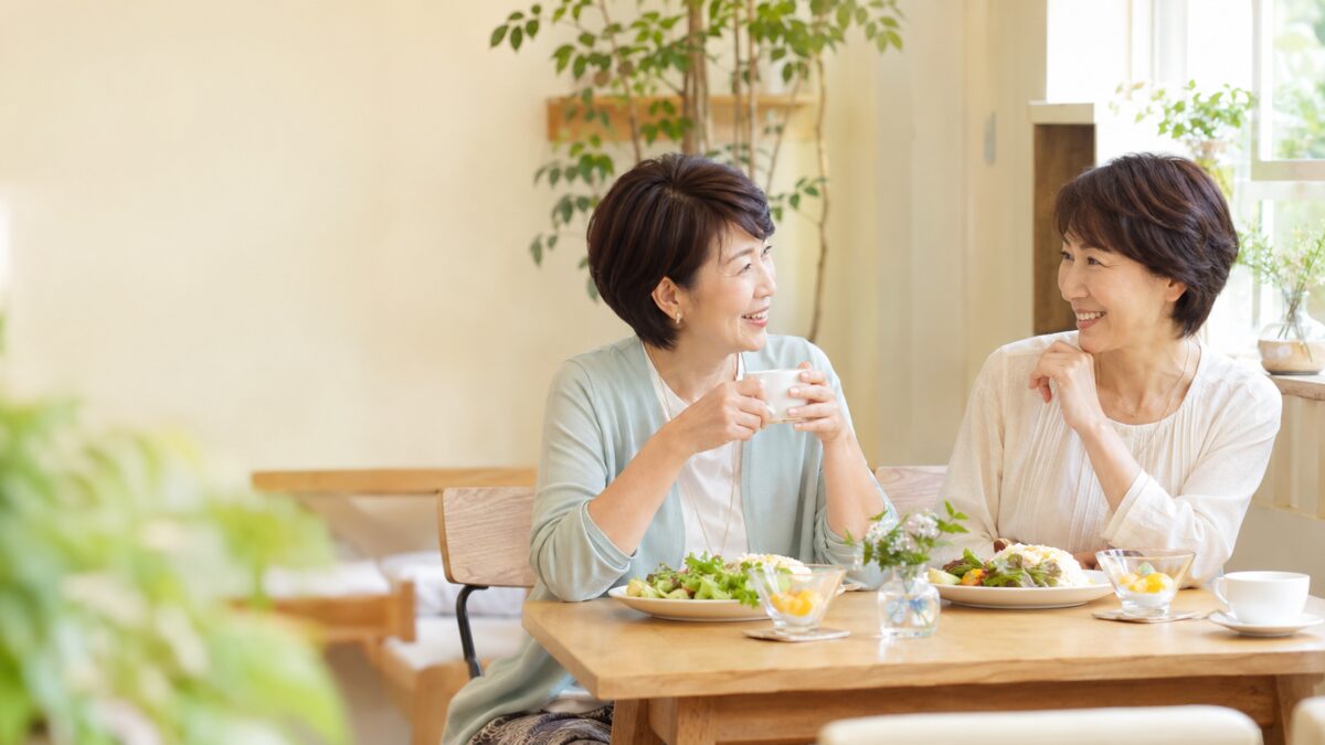 カフェでランチを楽しみながら会話する50代女性二人